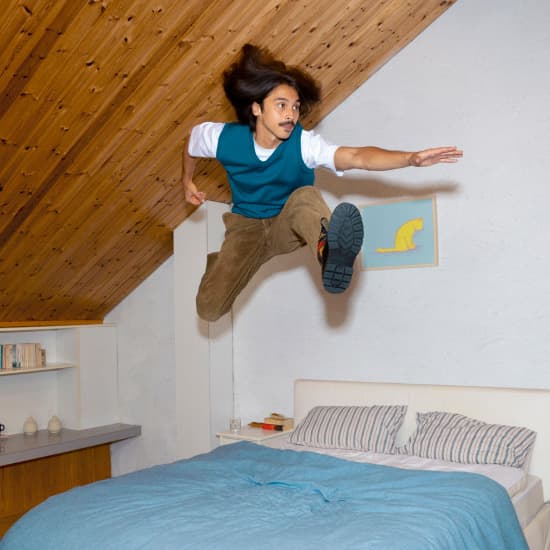 Man springt energiek op bed