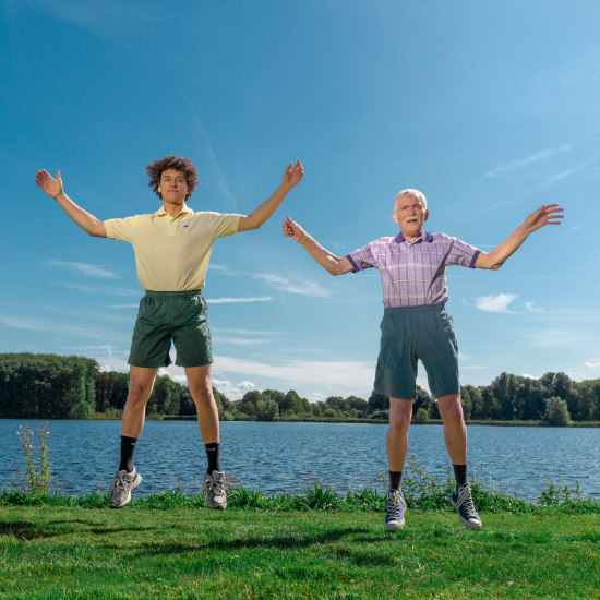 Twee mannen springen vrolijk bij een meer — Powerpeers, onderdeel van Vattenfall